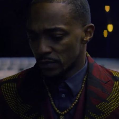 Anthony Mackie is wearing a red suit with a necklace.